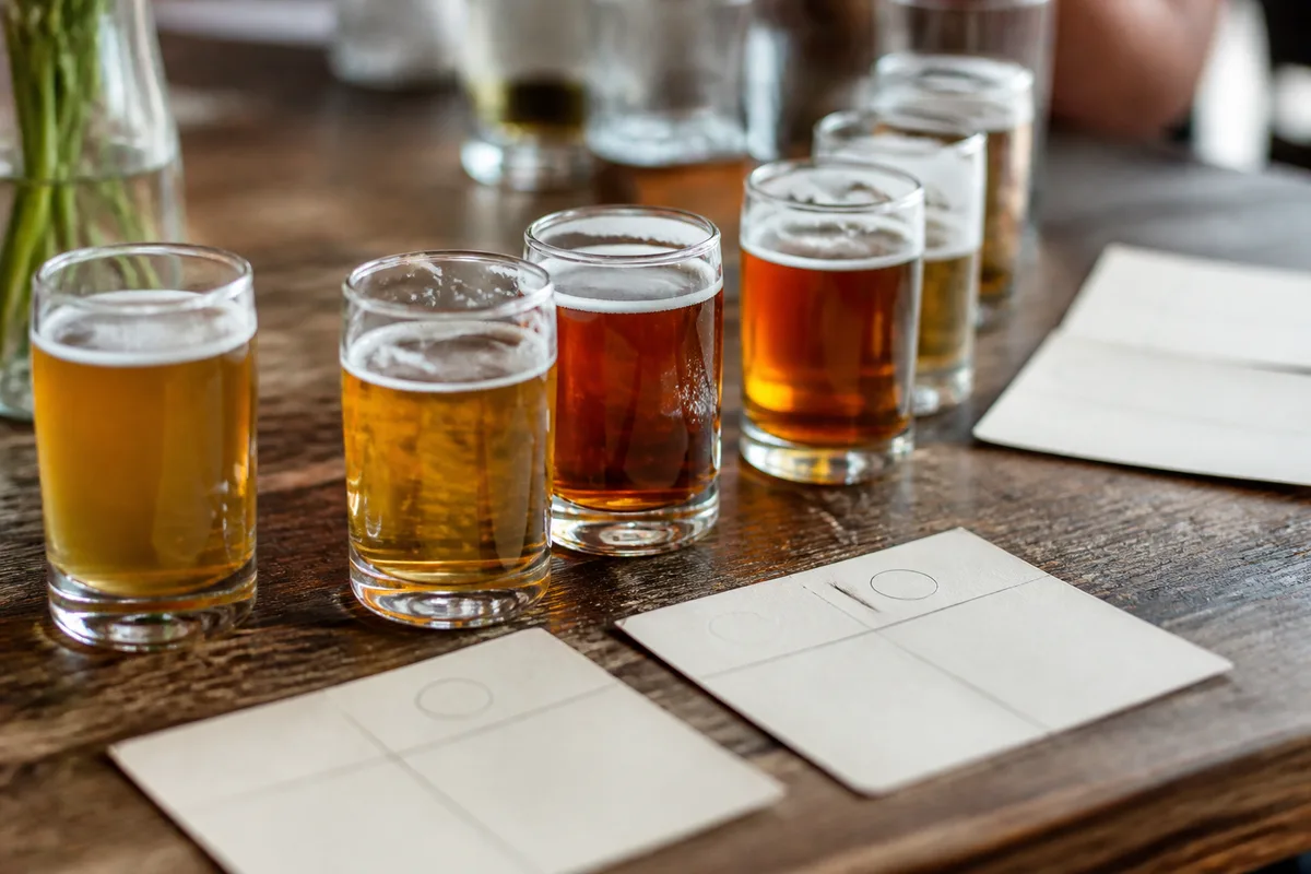 Verres de dégustation de petit format posés sur une table de bois avec fiches de tasting